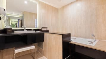 Un baño moderno con un espejo grande, un lavamanos y una banca.