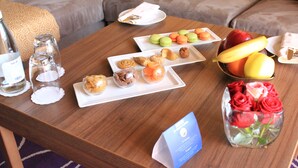 Una mesa de madera con diversos alimentos, un jarrón de rosas rojas y una tarjeta azul.