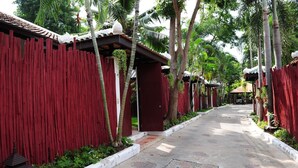 A pathway lined with red wooden fences and palm trees, leading to a covered area with a tiled roof. - Napalai Pool Villa Resort (Pattaya)