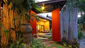 A traditional house with a red exterior, a bamboo fence, and a small garden with a Buddha statue. - Napalai Pool Villa Resort (Pattaya)