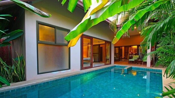 A swimming pool with tiled edges, a glass door entrance, and a room with a bed and a chair visible through the glass. - Napalai Pool Villa Resort (Pattaya)