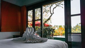 A hotel room with a bed, a large window, and a view of the outdoors. - Uma Stana Villa (Ubud)