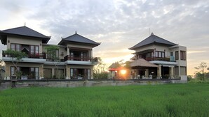 A traditional-style building with multiple balconies and a large open space in front. - Uma Stana Villa (Ubud)