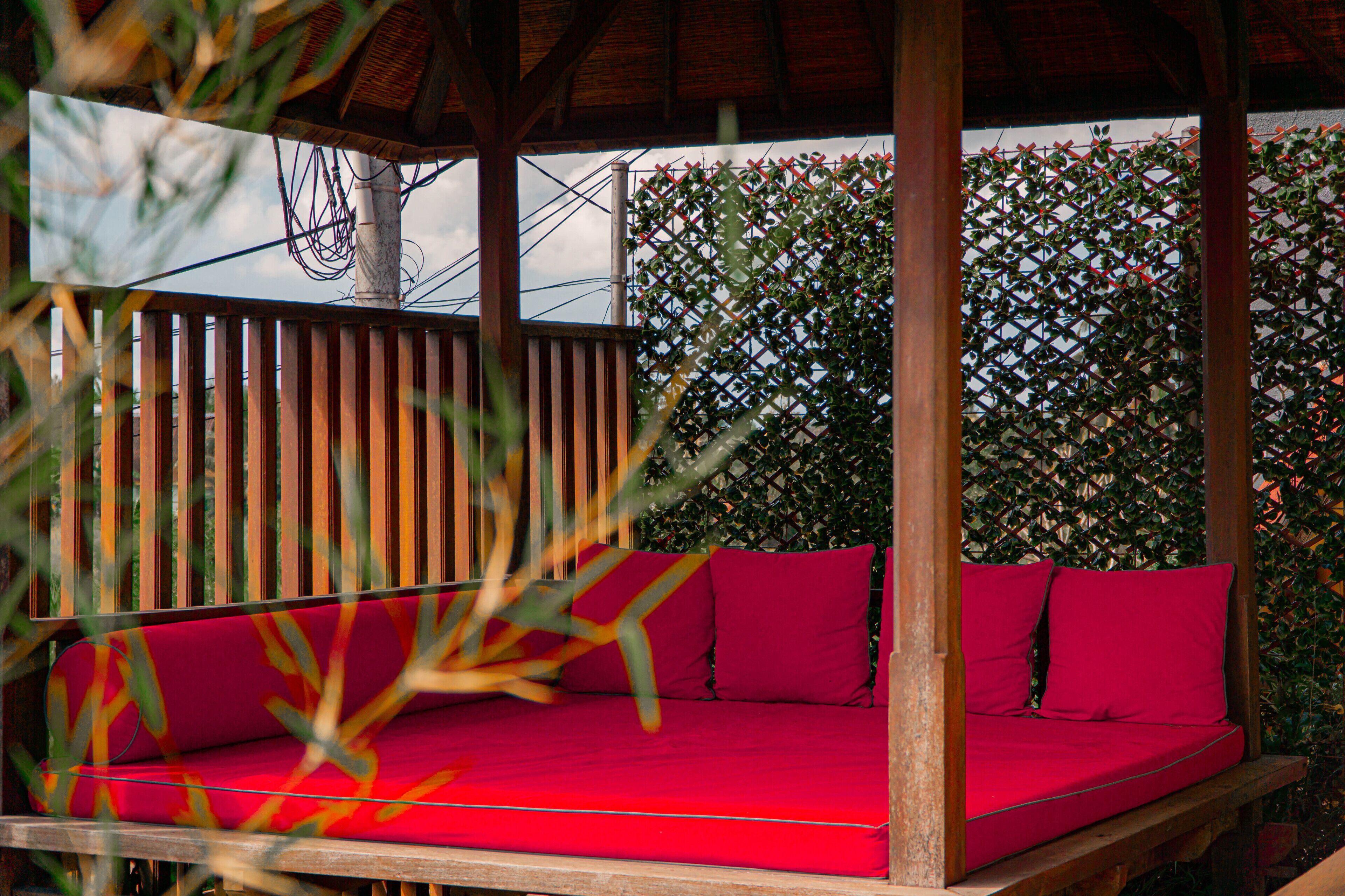 Una terraza de madera con un banco rojo acolchado.