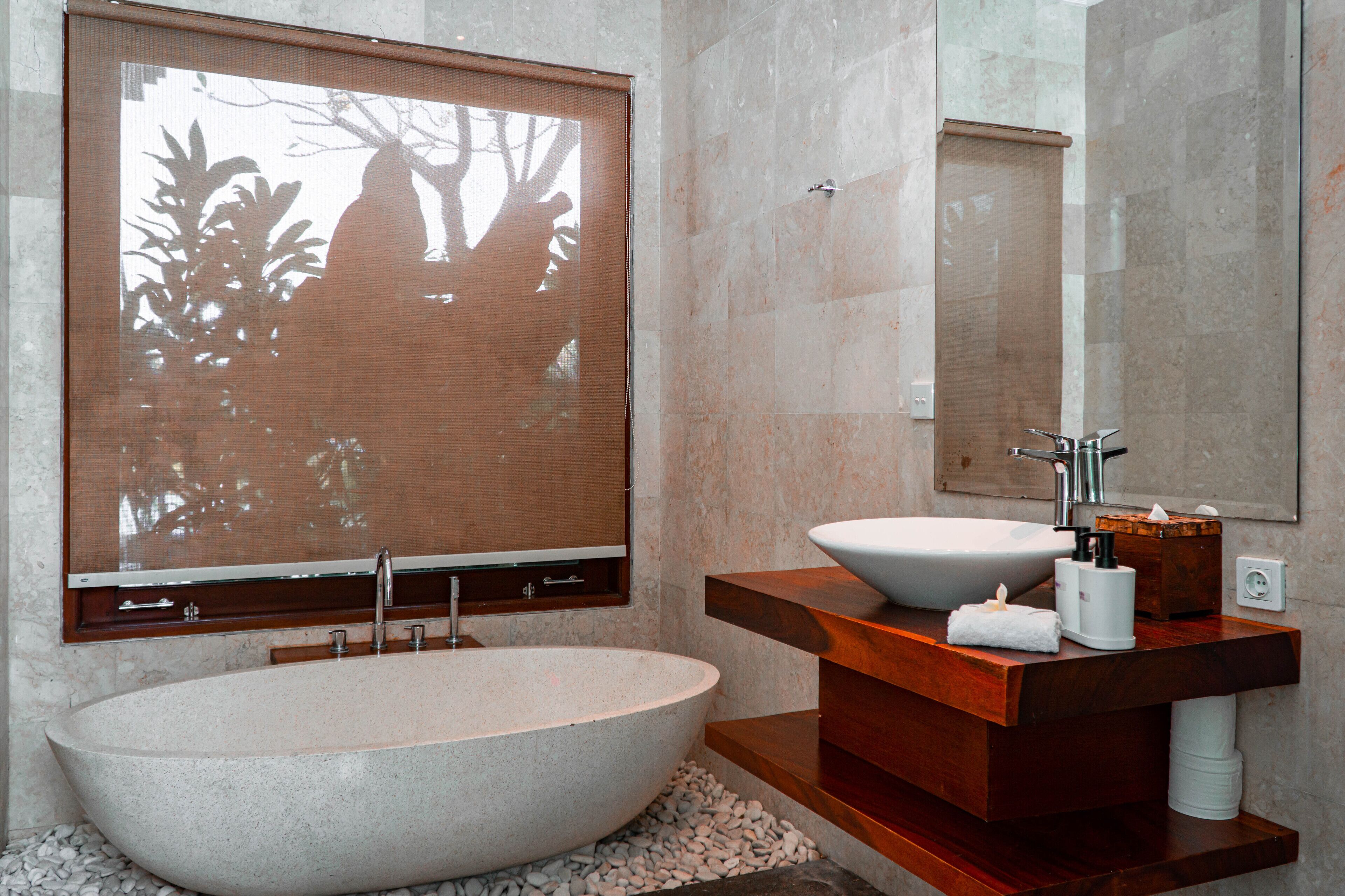 Ein modernes Badezimmer mit einer freistehenden Badewanne, einem Holzbidet und einem großen Spiegel.