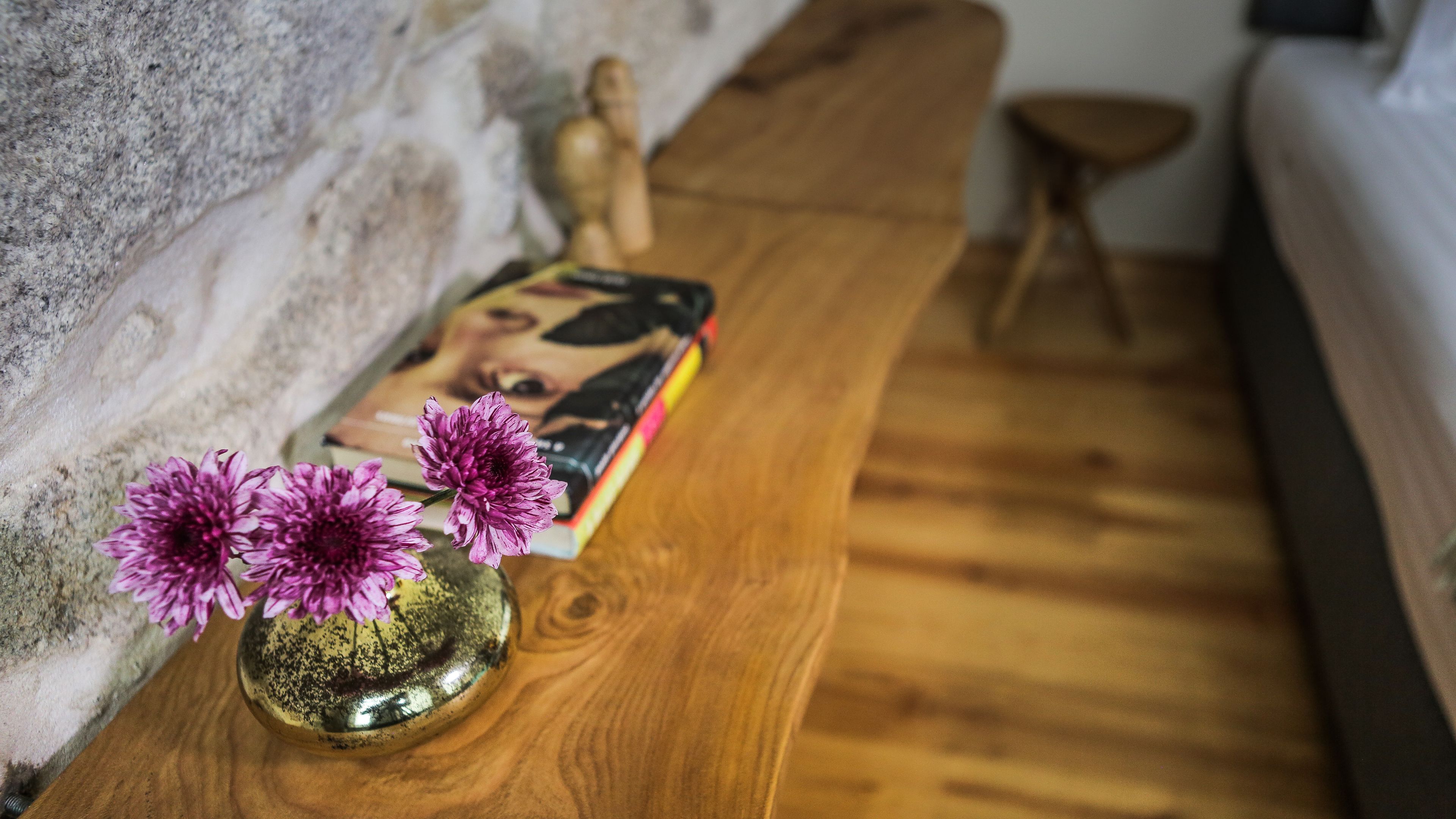 Un banc en bois, sur lequel sont posés un vase de fleurs et un livre.