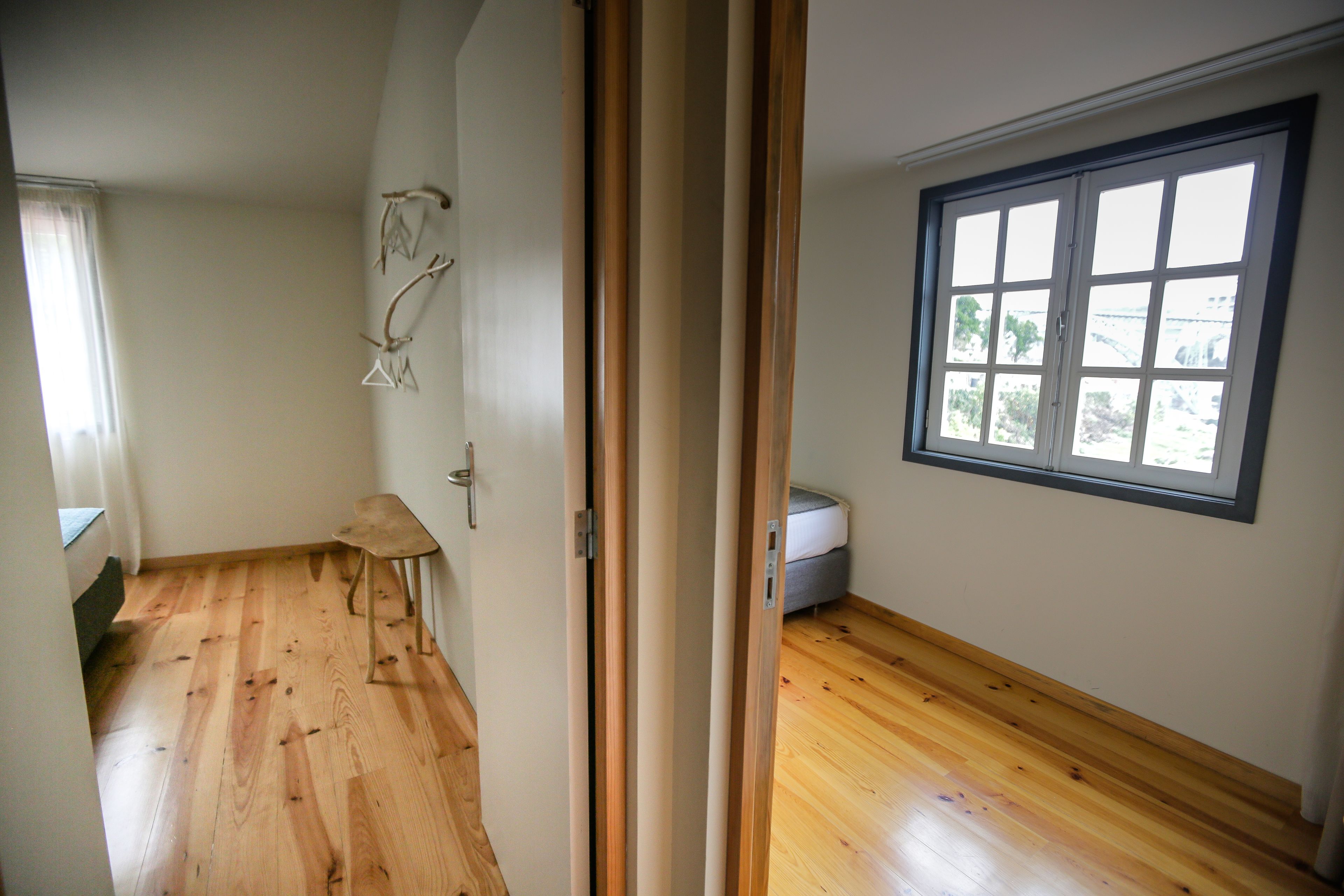 A room with wooden flooring, a window with blinds, and a door with a mirror.