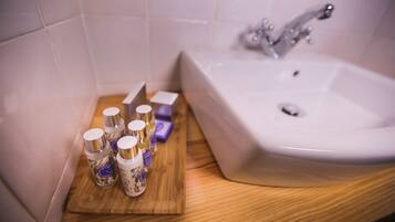 A bathroom with a white sink, a wooden vanity, and several bottles of toiletries.