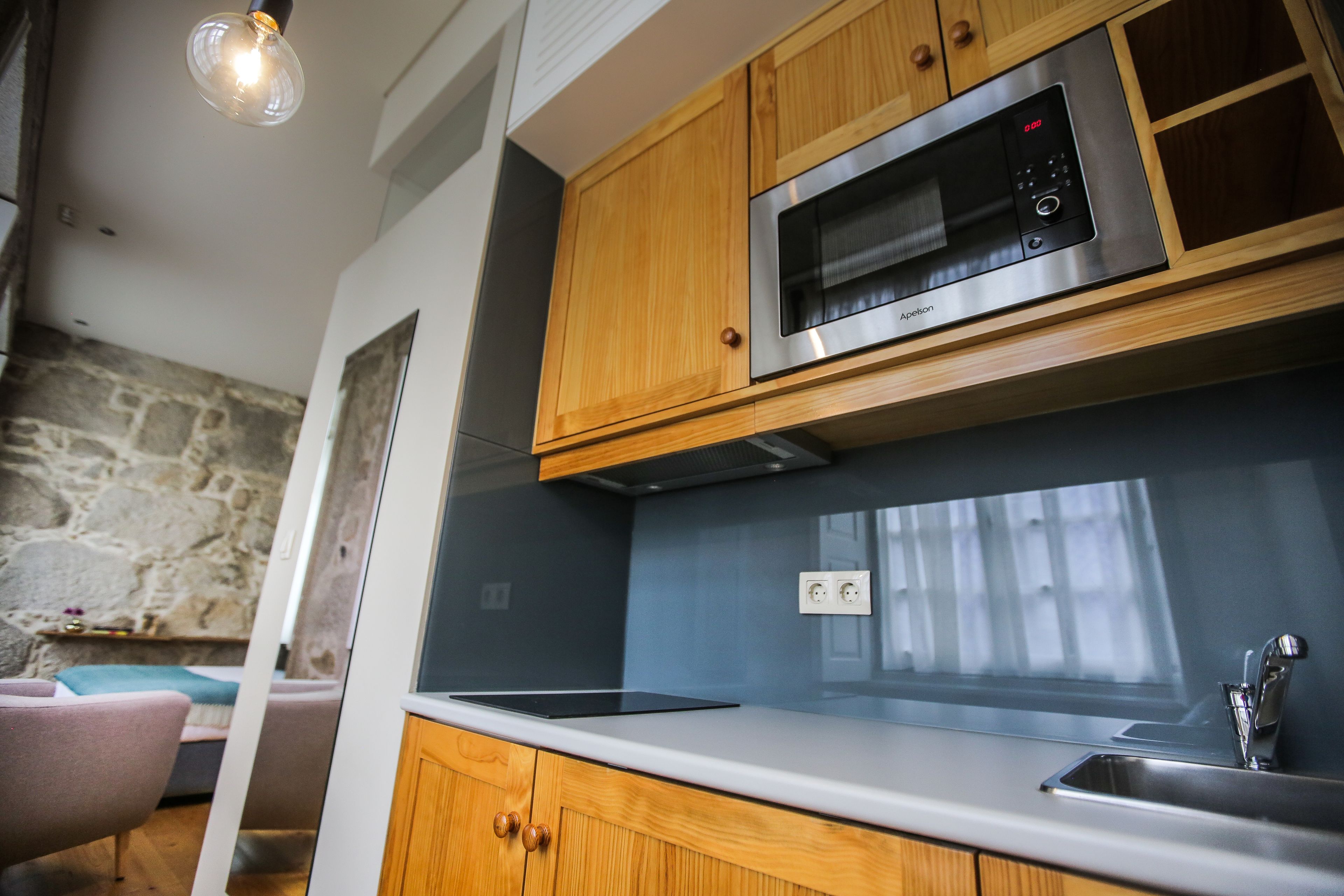 Una cocina moderna con armarios de madera, un microondas de acero inoxidable y un horno empotrado.
