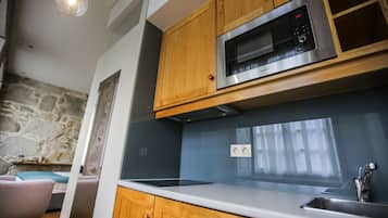 Una cocina moderna con armarios de madera, un microondas de acero inoxidable y un horno empotrado.