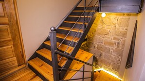 Un escalier en bois, un mur en pierre et un luminaire.