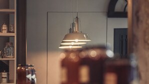 Une cuisine dotée d’un éclairage suspendu, d’un réfrigérateur et d’un meuble contenant des bocaux.
