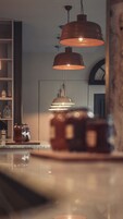 A kitchen with pendant lighting, a refrigerator, and a cabinet with jars.
