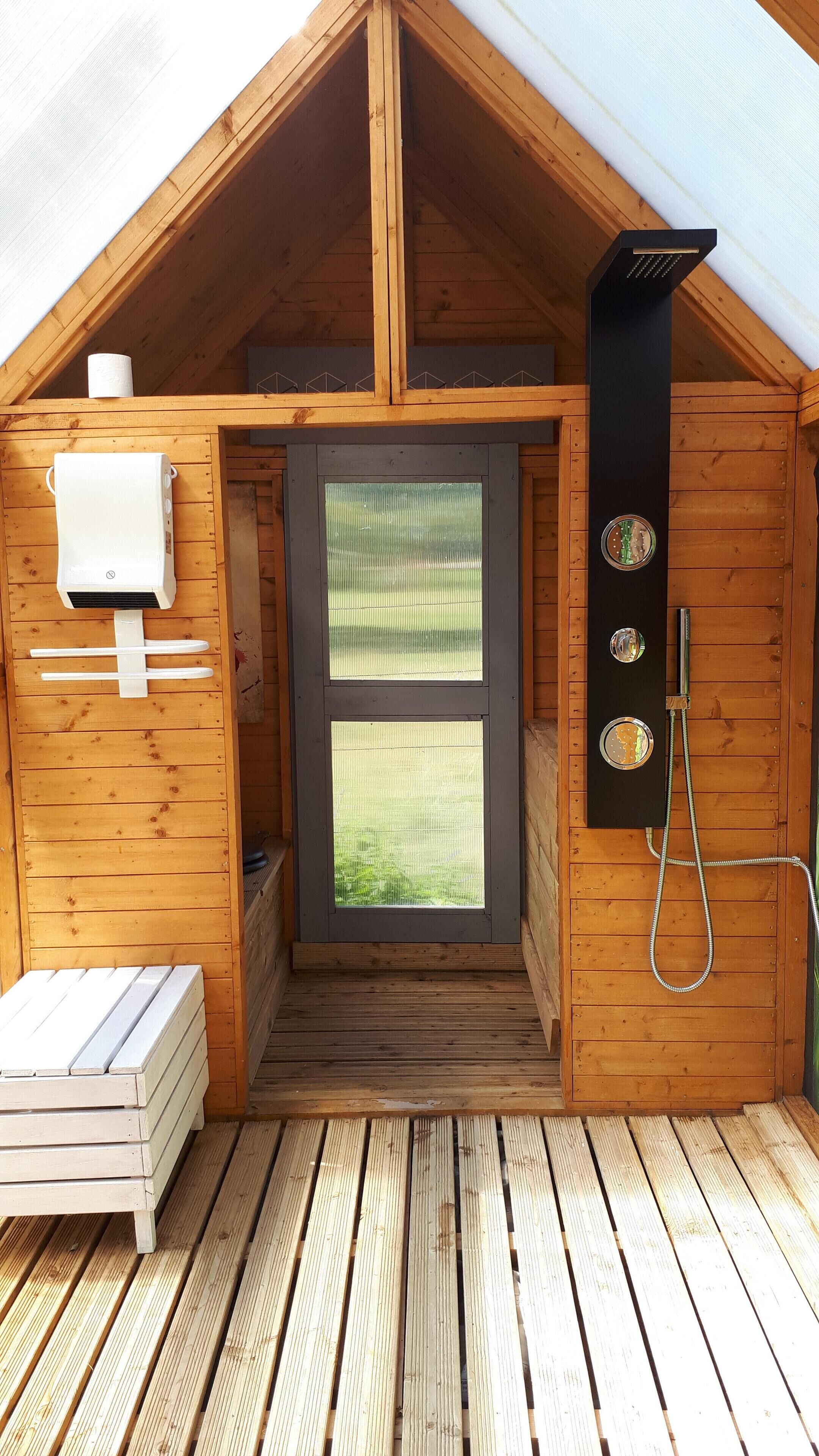Una cabaña de madera con una entrada pequeña, ducha y sauna.