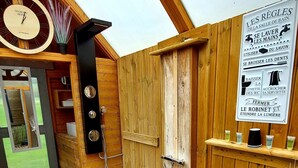 Una terraza de madera con una puerta de madera, un reloj y un letrero con indicaciones.