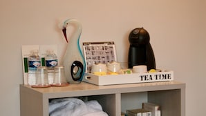 Een theeset met een container in de vorm van een zwaan, een koffieapparaat en een dienblad met de tekst 'TEA TIME' op een plank.