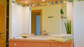 A bathroom with a white sink, a mirror, and a potted plant.