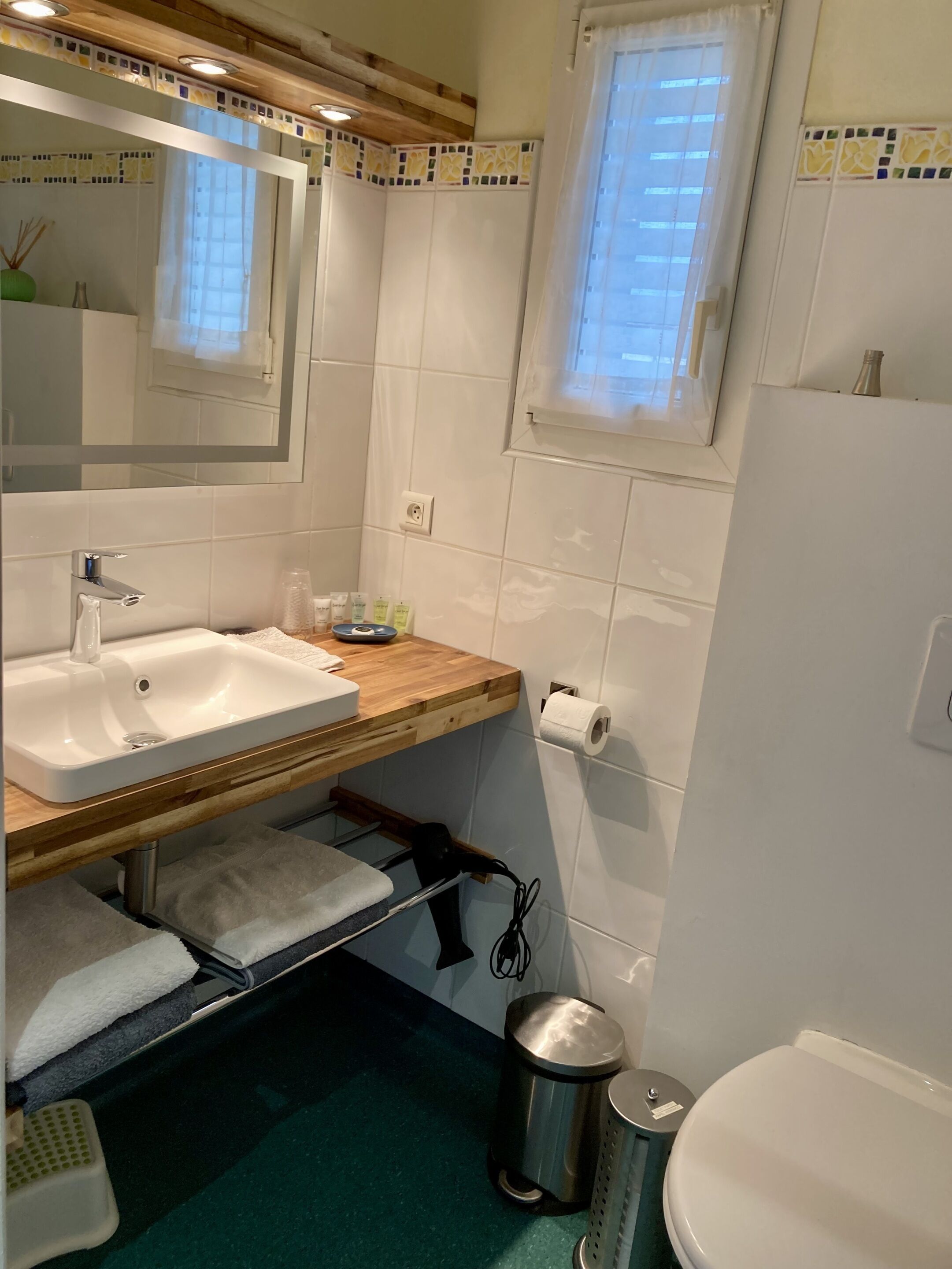 A bathroom with a white sink, wooden countertop, mirror, and a window with curtains.