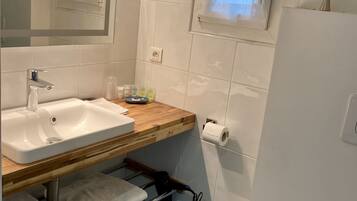 A bathroom with a white sink, wooden countertop, mirror, and a window with curtains.