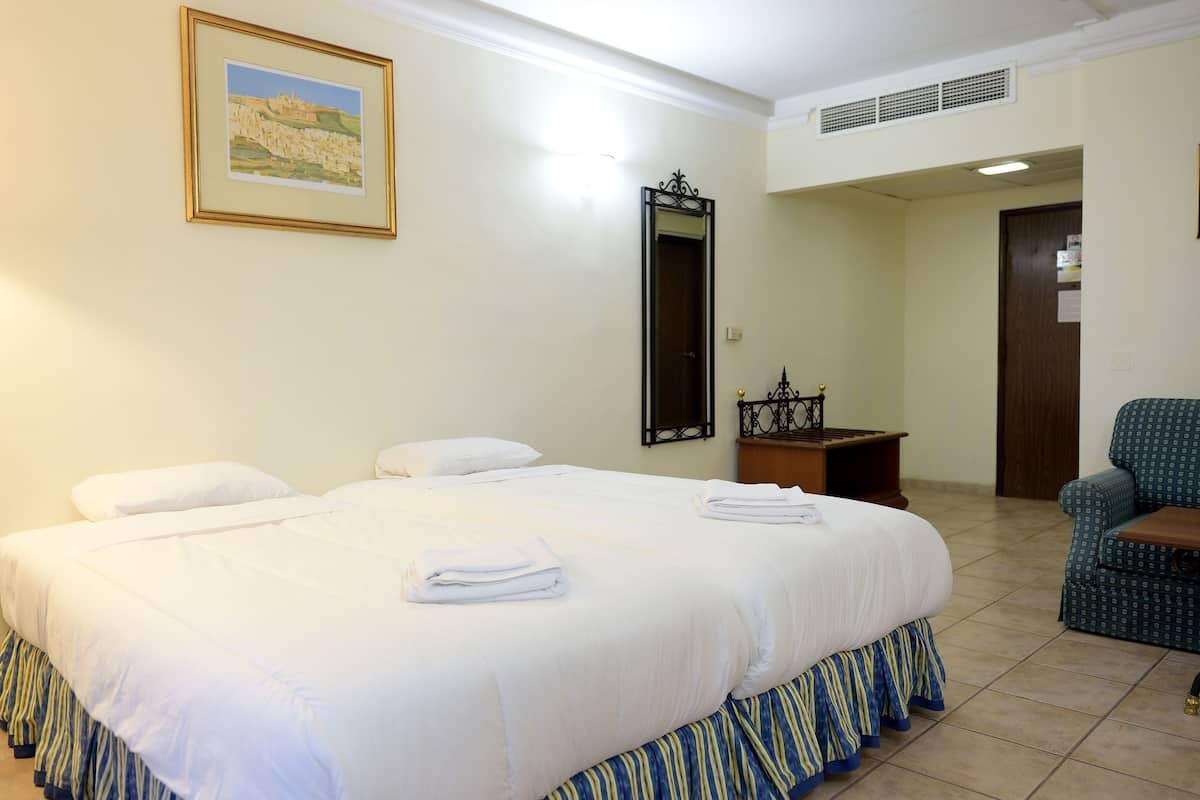 Une chambre d’hôtel avec un grand lit, une chaise, une petite table et un miroir.