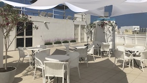 An outdoor patio with white wicker furniture and potted plants. - Oriana Hotel (St. Paul's Bay)