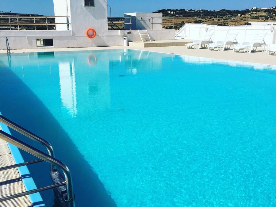 Een binnenzwembad, een buitenzwembad en ligstoelen