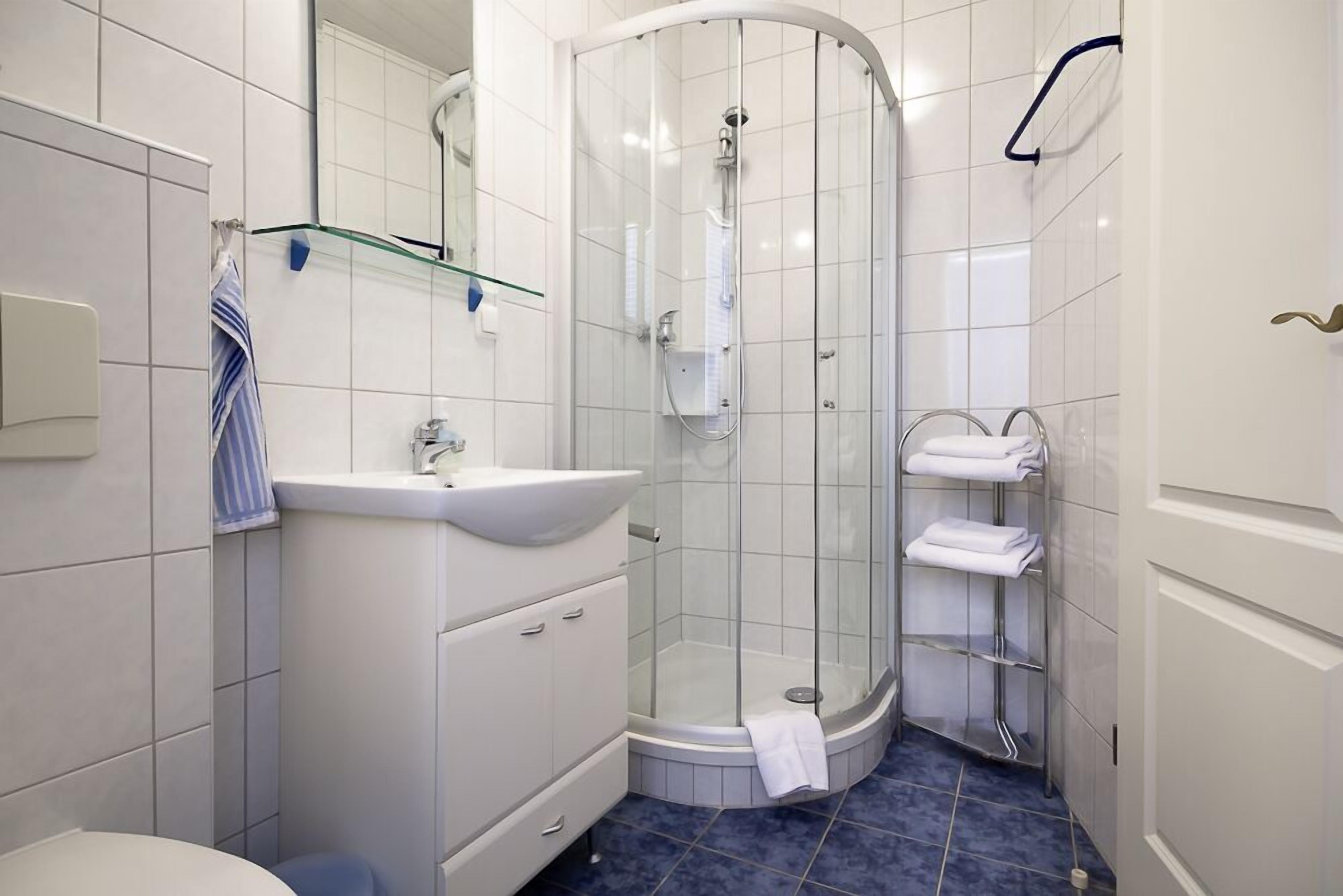 Ein modernes Badezimmer mit einer Glaskabine zur Dusche, einem weißen Waschbecken und einem Handtuchhalter.
