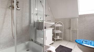 A modern bathroom with a glass shower enclosure, a white sink, and a bathtub with a blue design.