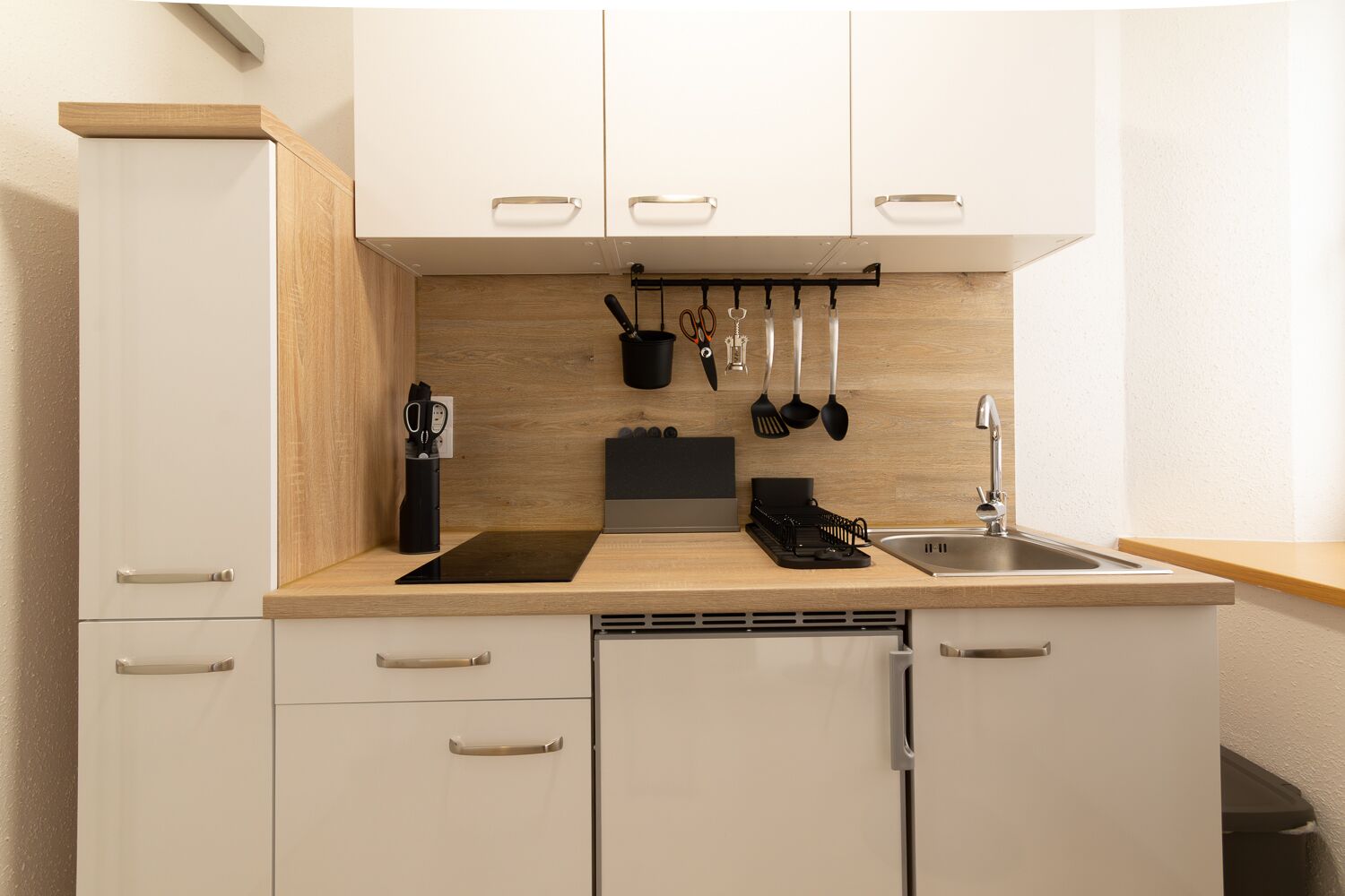 A modern kitchen with white cabinets, a wooden countertop, and a built-in dishwasher.