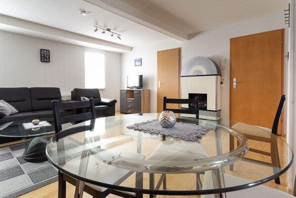 A modern living room with a glass table, black chairs, a black sofa, and a TV stand. - Feriendorf Slawitsch (Bad Sulza)