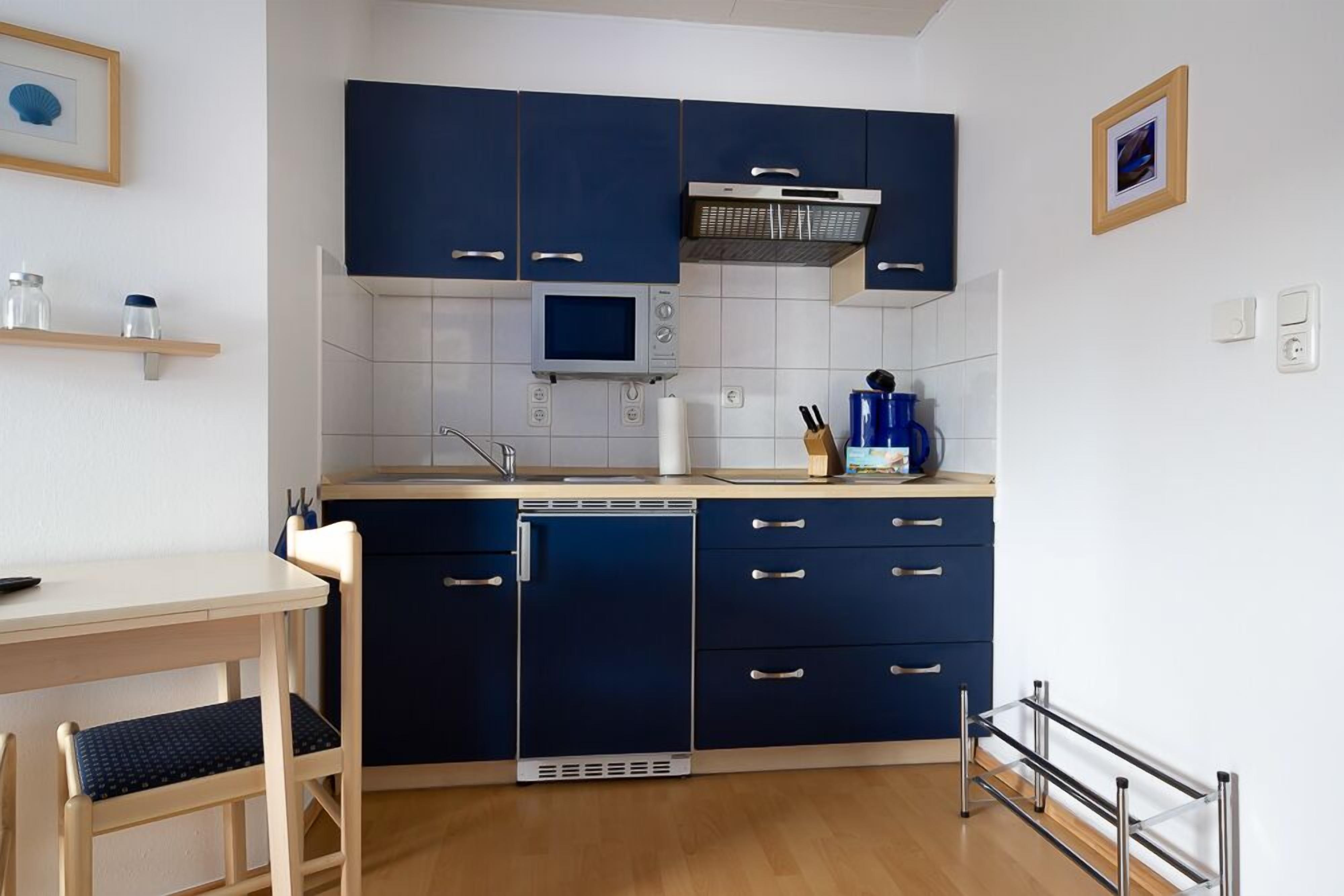 A compact kitchen with dark blue cabinets, a microwave, and a dishwasher.