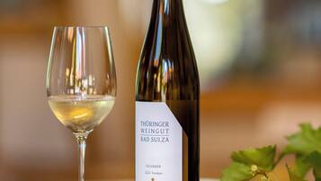Una bottiglia di vino etichettata "Thüringer Weingut Bad Sulza" e un bicchiere da vino su un tavolo con dei tappi di sughero.