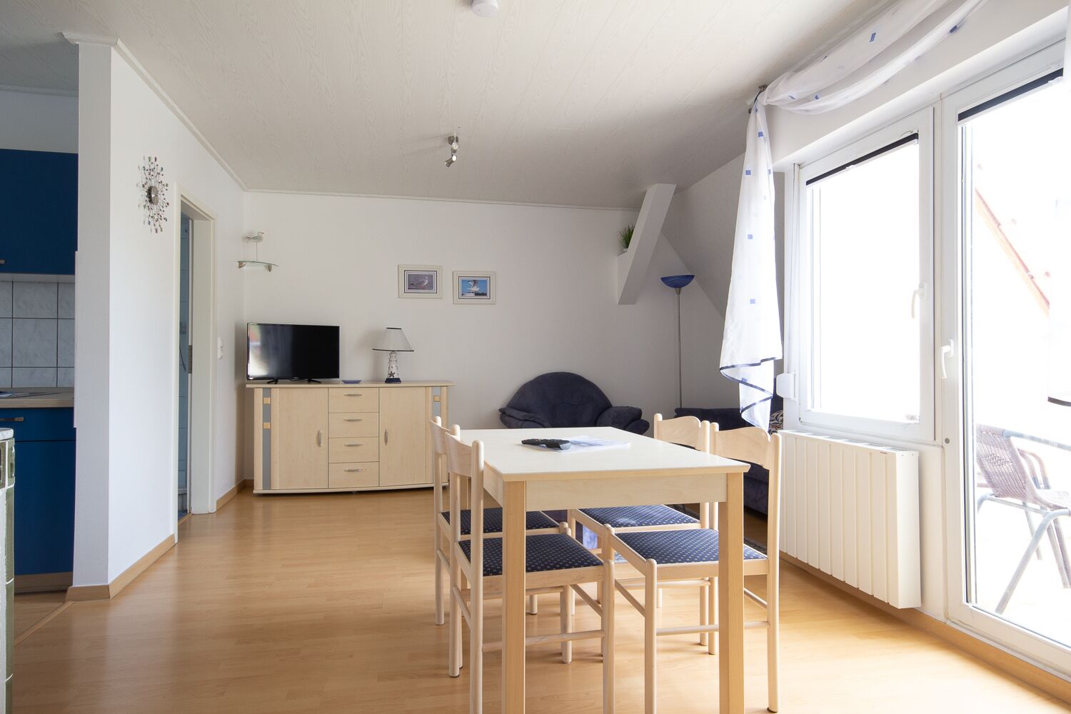 A compact living space with a dining area, a kitchenette, and a large window providing natural light.