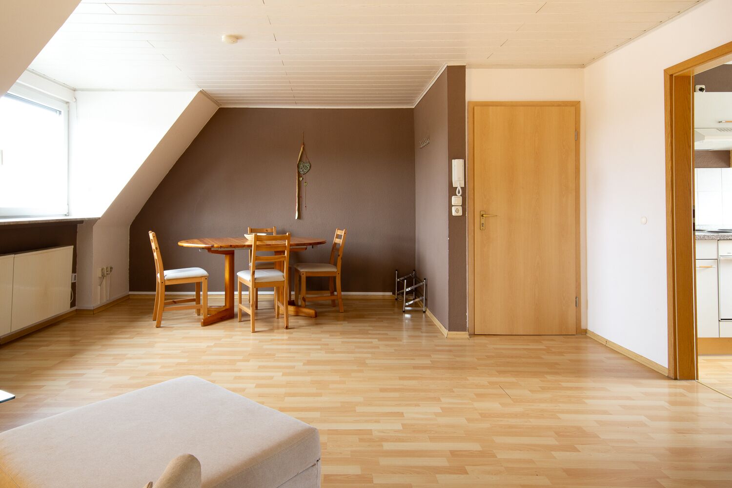 Una habitación amplia con techo alto, un comedor con muebles de madera, una puerta y vistas a una zona de cocina.