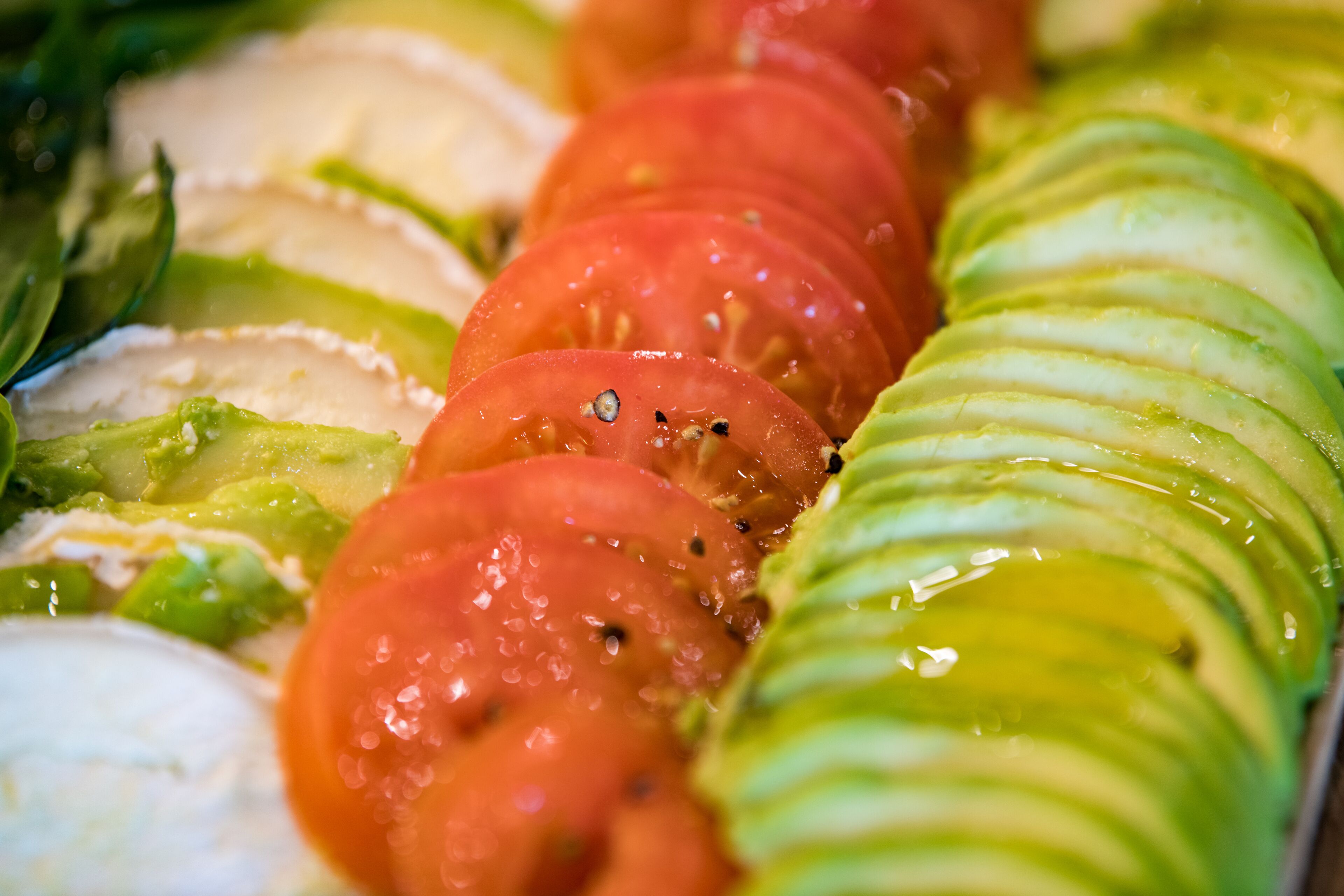 Gros plan sur une salade de tomates et de concombres coupés en tranches, où l’on peut voir les graines et la présence de jus.