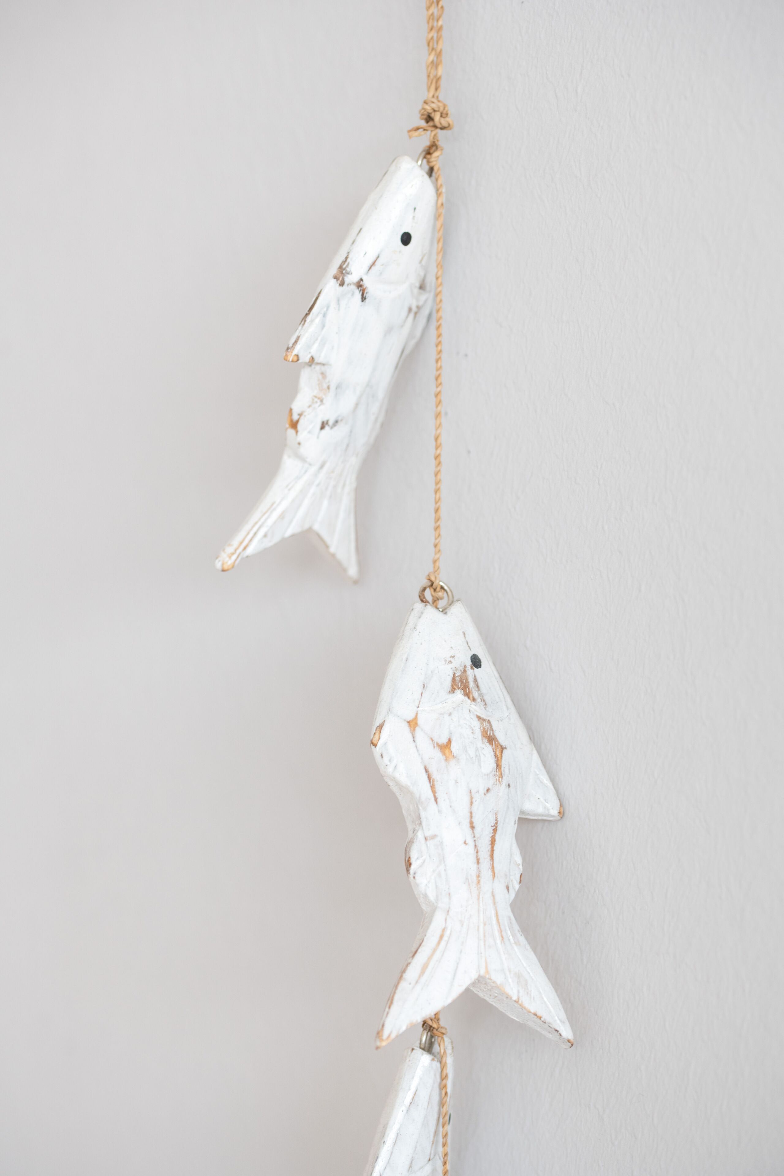 A wall with two white fish-shaped decorations hanging from a rope.