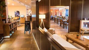 A modern hotel lobby with a seating area, a reception desk, and a dining area. - Ko'Ono Hotel und Restaurant (Konstanz)