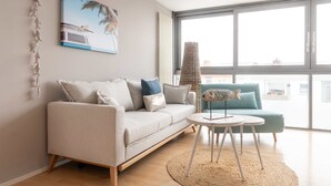 A modern living room with a sofa, a round coffee table, and a view of the city through large windows. - Ko'Ono Hotel und Restaurant (Konstanz)