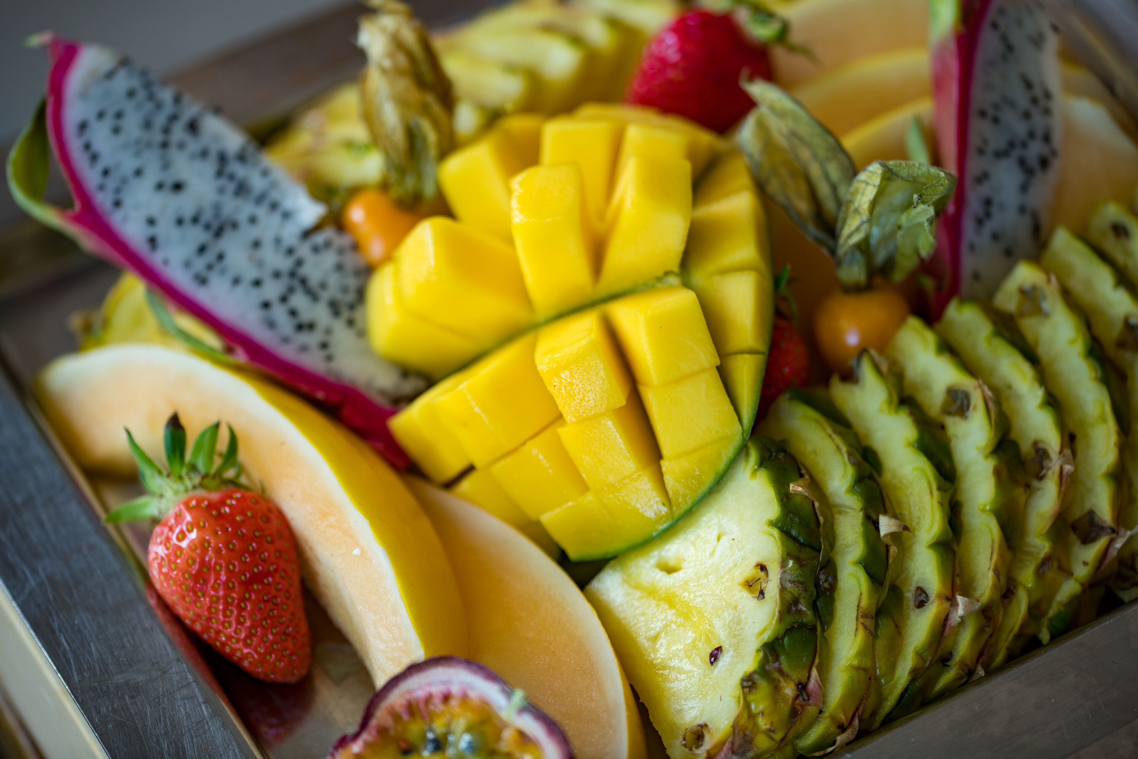 A variety of fresh fruits including mango, dragon fruit, and strawberries.