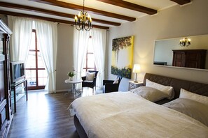 A hotel room with a large bed, a desk with a chair, a small table with a lamp, and a painting on the wall. - Görlitz Apartment - In der Bütt (Görlitz)
