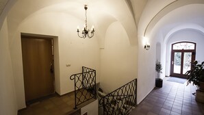 Una escalera con barandilla de hierro forjado, un candelabro y una puerta de madera en la parte superior.