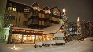 A hotel with a snow-covered entrance, illuminated by string lights, and a sign indicating it is the Bansko hotel.