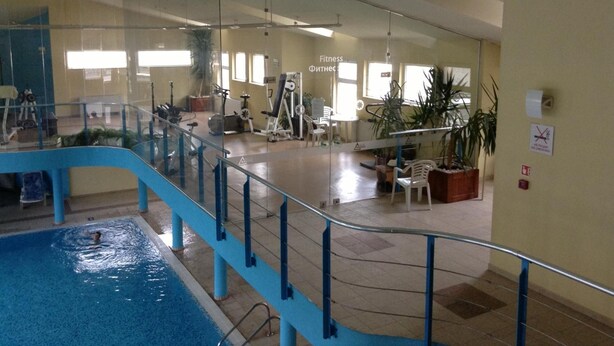 An indoor swimming pool with a glass barrier, exercise equipment, and a staircase.