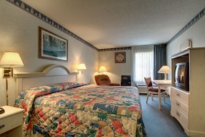 Habitació d'hotel amb llit, escriptori, televisió i dues làmpades.