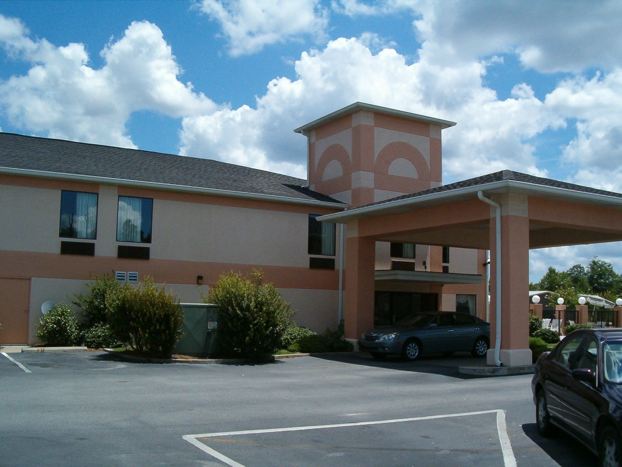 A building with a parking lot, a covered entrance, and a car parked inside.