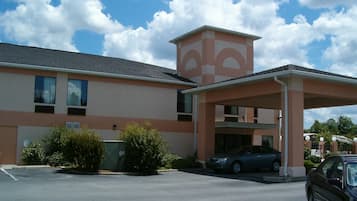 A building with a parking lot, a covered entrance, and a car parked inside.
