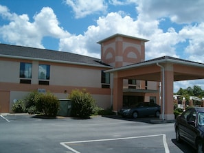 A building with a parking lot, a covered entrance, and a car parked inside.