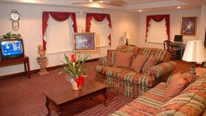 Sala de estar com sofá, mesa de centro, televisão e planta decorativa.