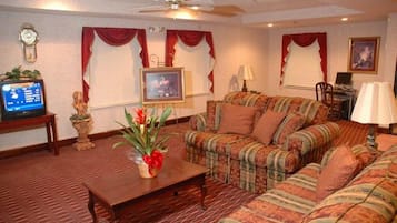 A living room with a sofa set, a coffee table, a television, and a decorative plant.