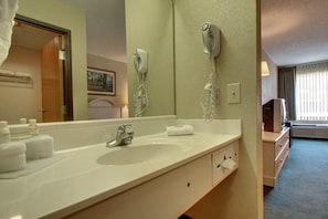 Un bany d'hotel amb un vàter, dispensador de tovalloles i un assecador de cabells fixat a la paret.